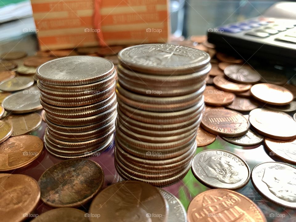 Scattered us coins in the table including pennies, quarters, dimes, nikle, cents. Calculator, coins envelopes.