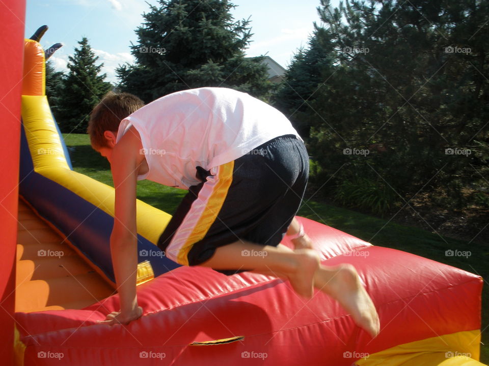 Jump Right in. Boy, leaping over the side of a blow up obstacle course. 