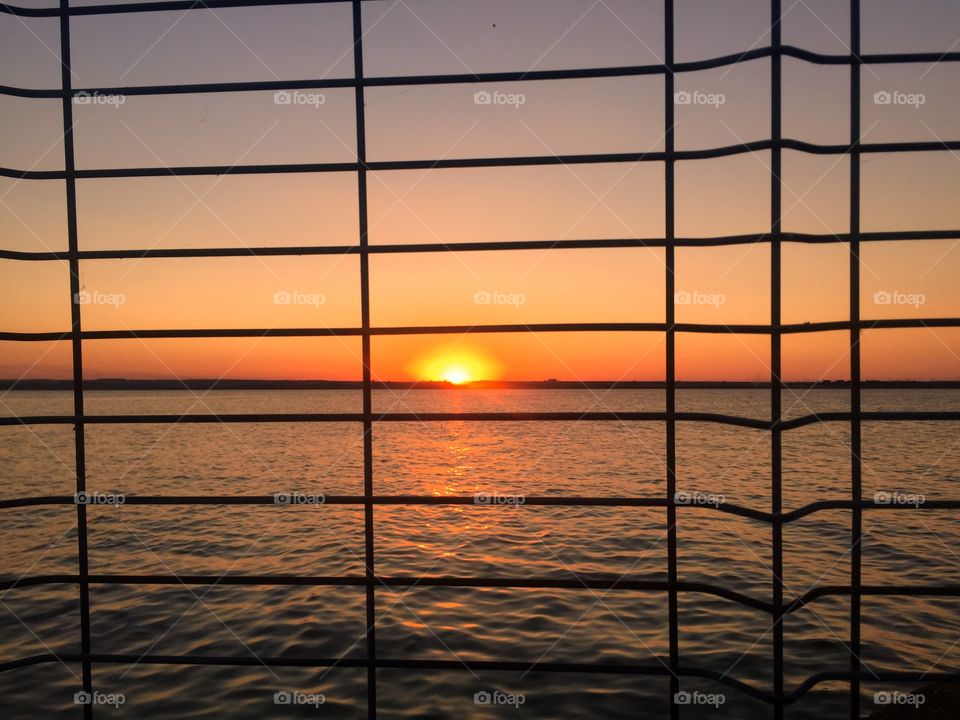 Sunset seen through silhouette fence