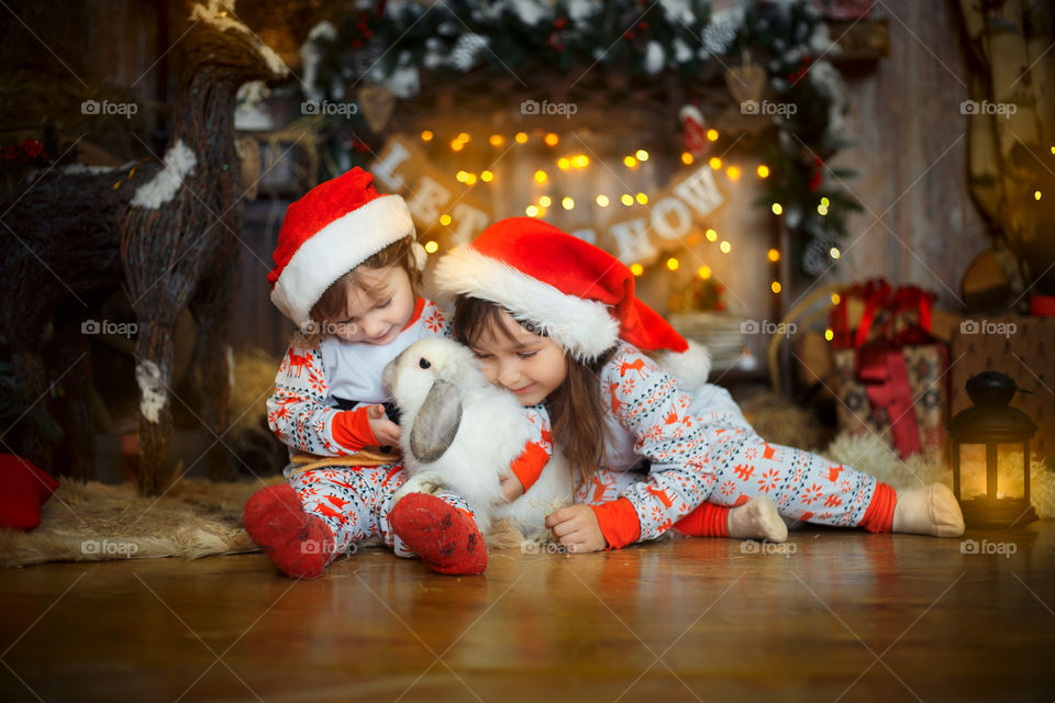 Little sisters near fireplace at Christmas Eve 