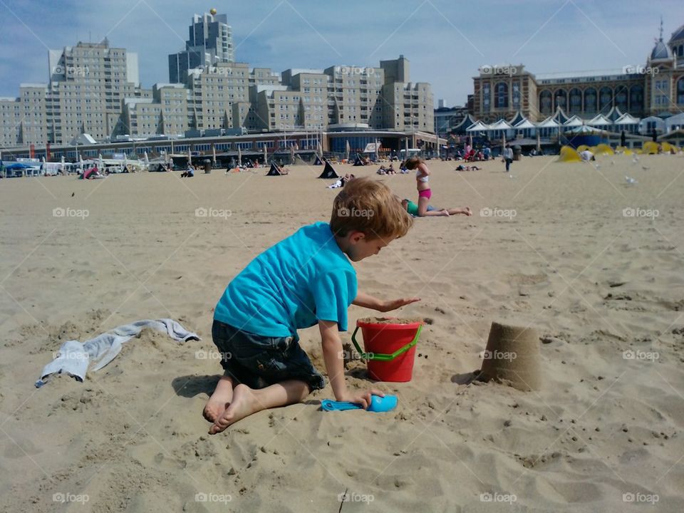 little boy on beach playing with sand shovel 