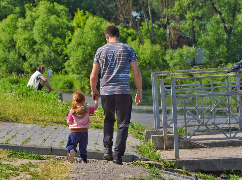 father and daughter walking along the city embankment