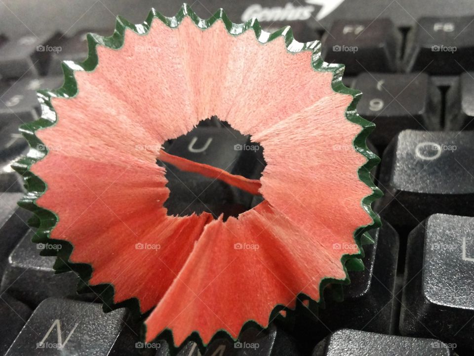 Green-orange, pencil sharpener on black keyboard.