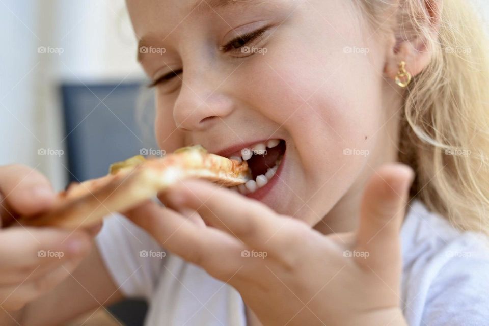A blonde hair toddler eating pizza 