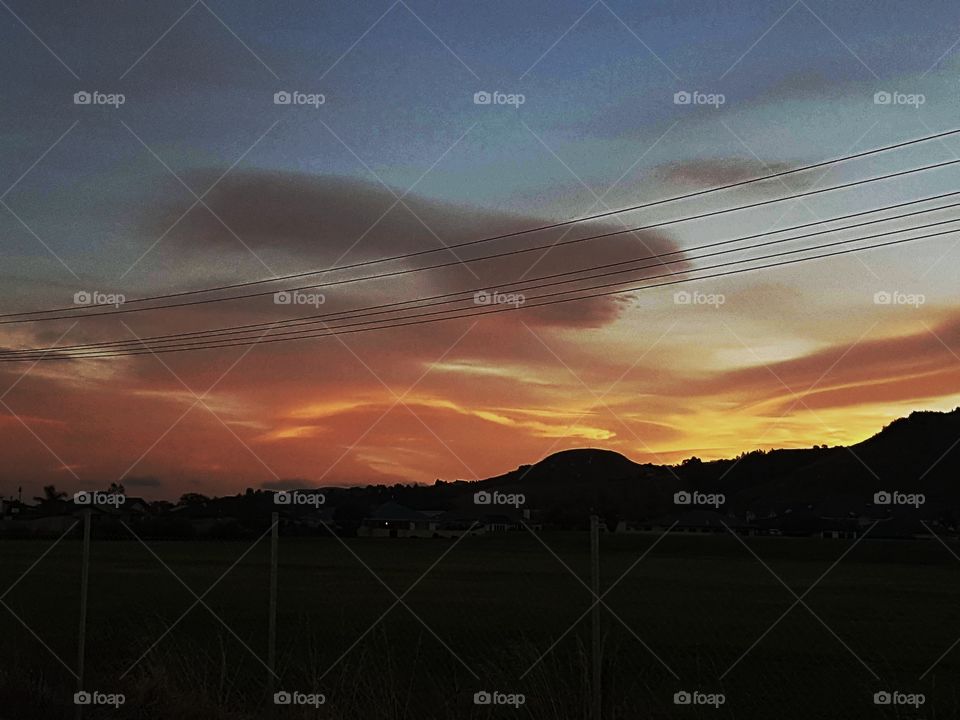A sunset over the sugar loaf hill in Taradale Napier. The cloud formations look like a girl in vibrant orange yellow blues etc.