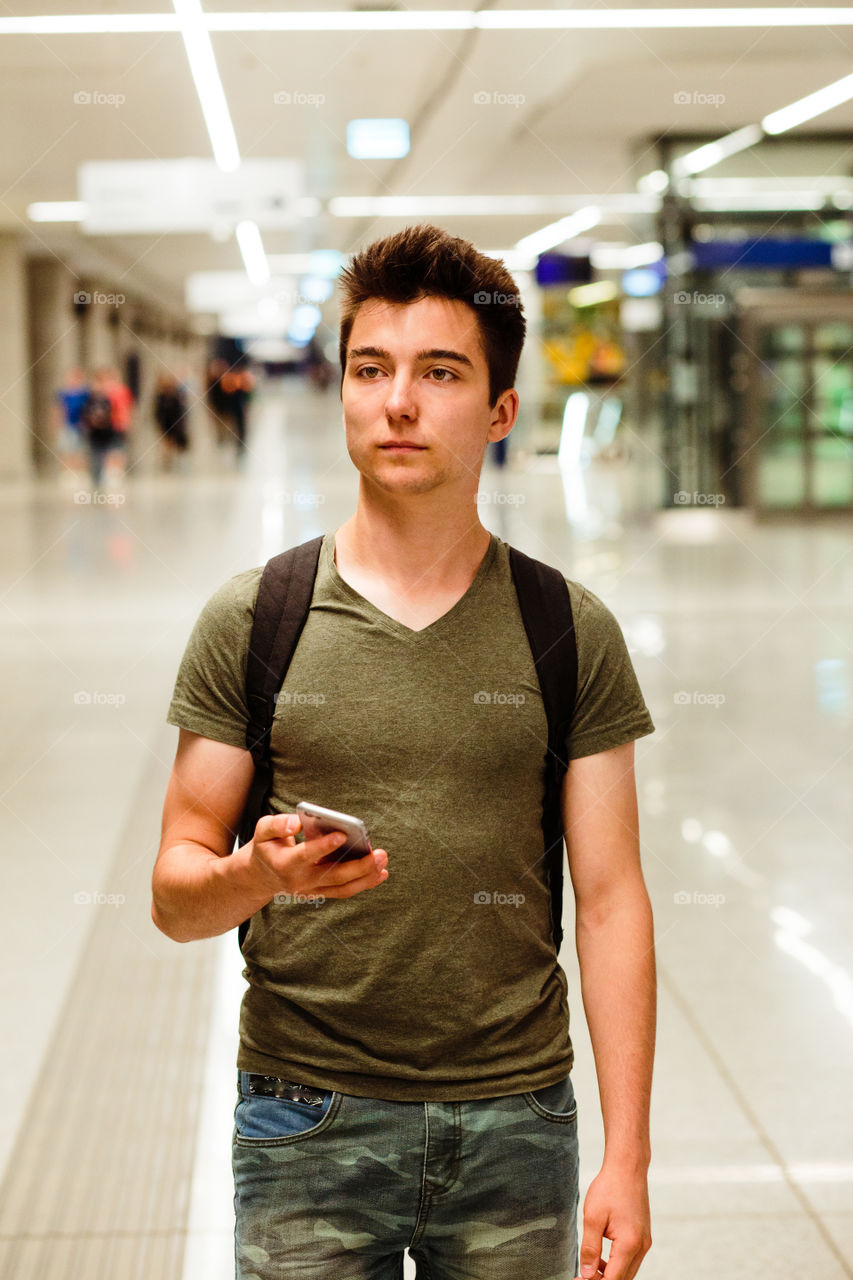 Young man standing in the railway station, planning a travel, travelling with backpack