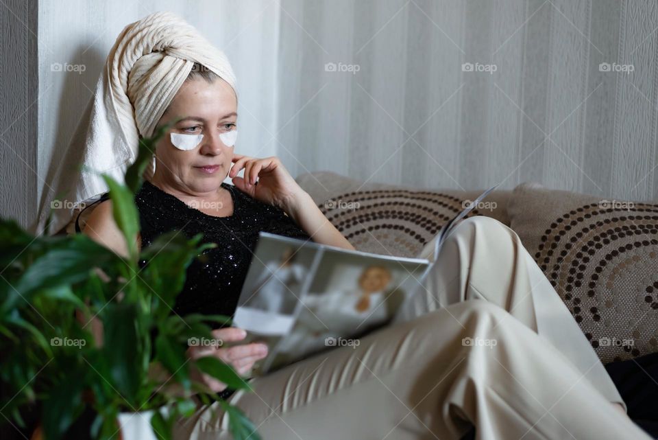 Home beauty salon woman making eye patches mask and reading magazine on sofa