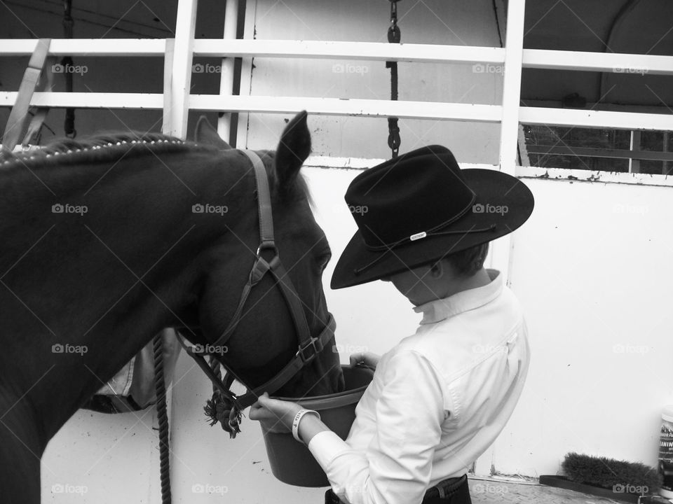 A young man watering his horse in between events at a horse show from the woods of South Georgia. 