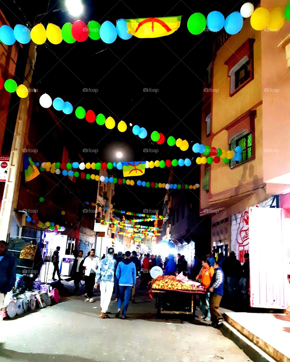 A picture taken in one of the streets of Ait Melloul, Agadir, on January 13, 2025, during the celebration of the Amazigh New Year (Yennayer). The image captures people dressed in colorful traditional clothing,