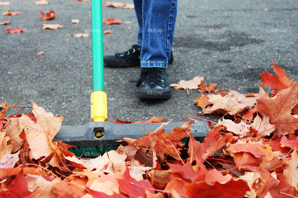 Teenager sweeping colorful fall leaf