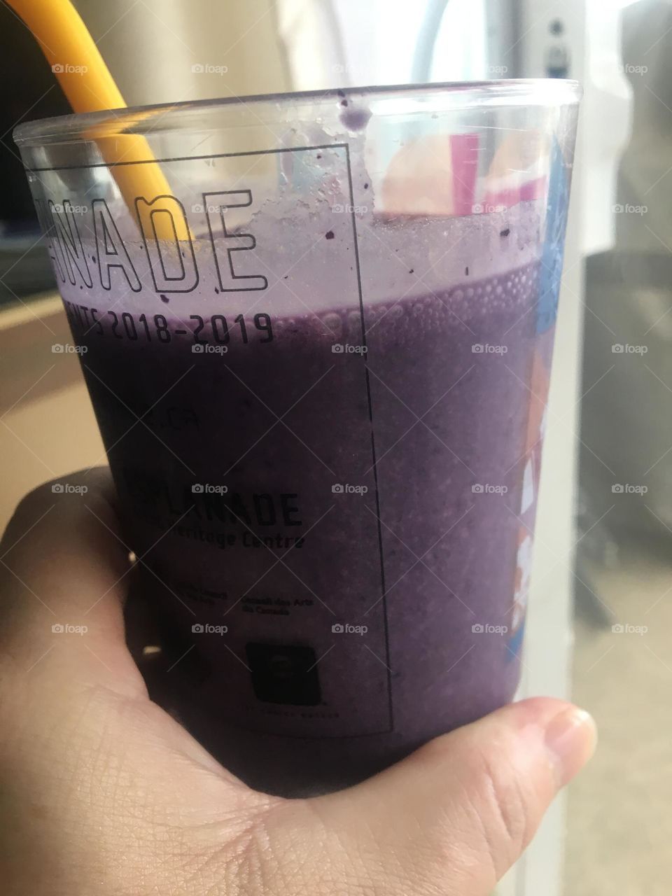Middle aged womens hand, holding a mixing cup with a blueberry smoothie in it