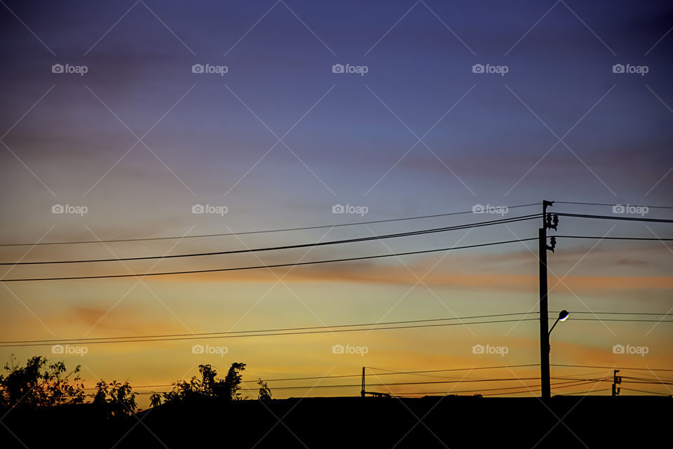 Beautiful light of Sunset with clouds in the sky reflection behind the building and trees.