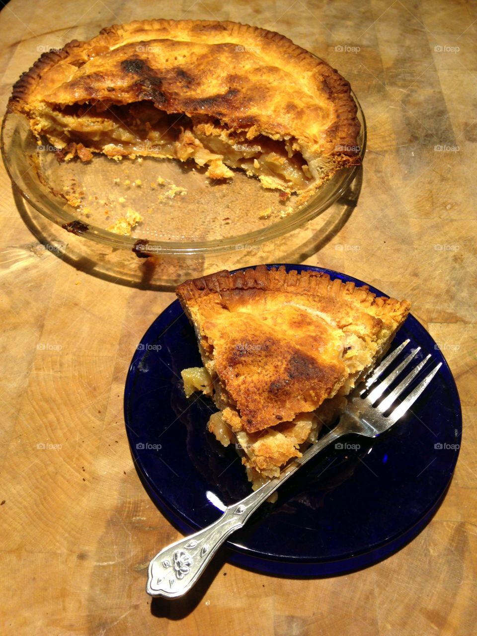 Homemade apple pie with slice cut out and served on plate with fork.