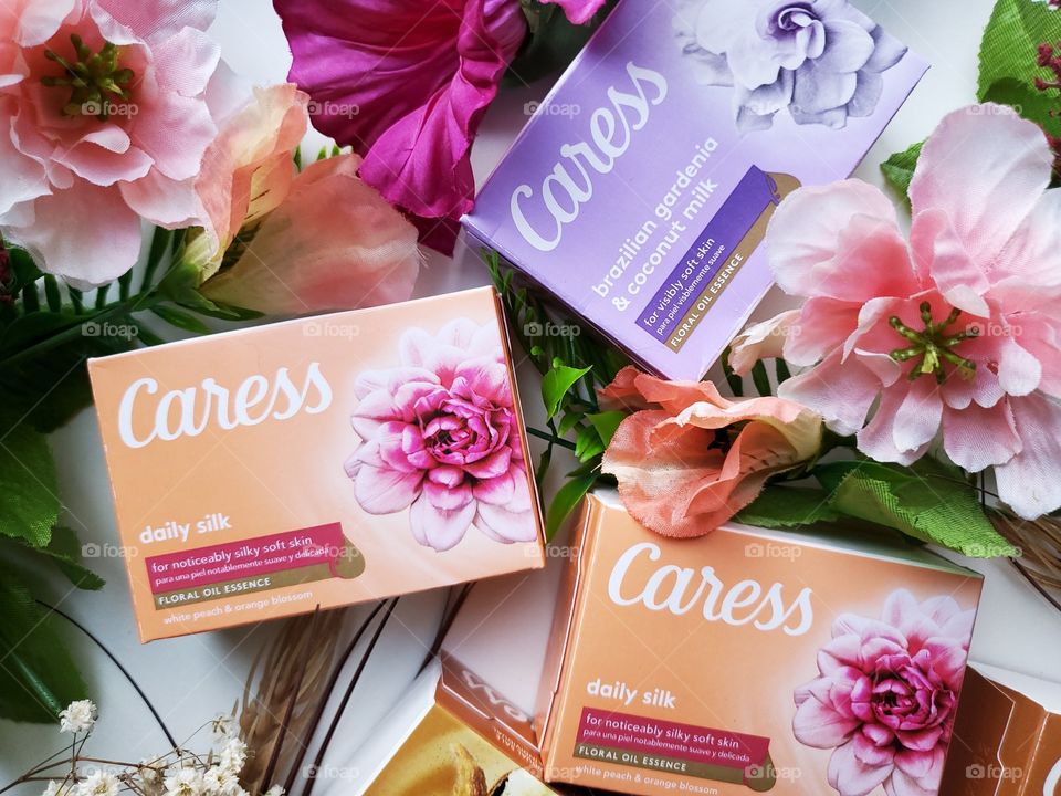 The new look Caress bars single pack: brazilian gardenia & coconut milk and daily silk, surrounded my complementary florals on a white background.