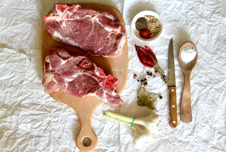 Raw meat on a wooden cutting board with spices