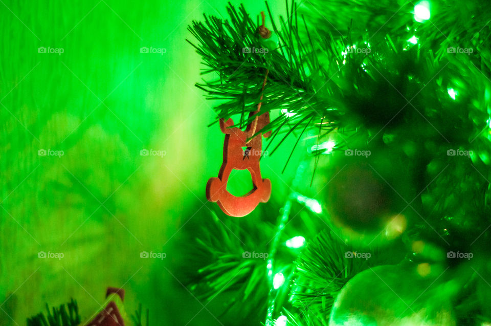 Red wooden horse as a Christmas tree decoration element and green light 