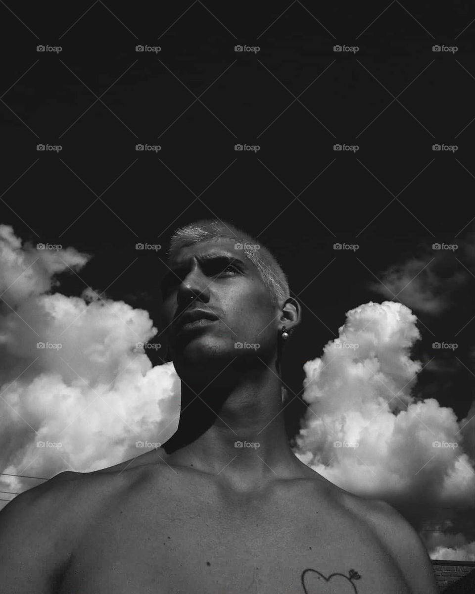 Black and white self Portrait of a young man, with clouds behind him. Beautiful selfie.