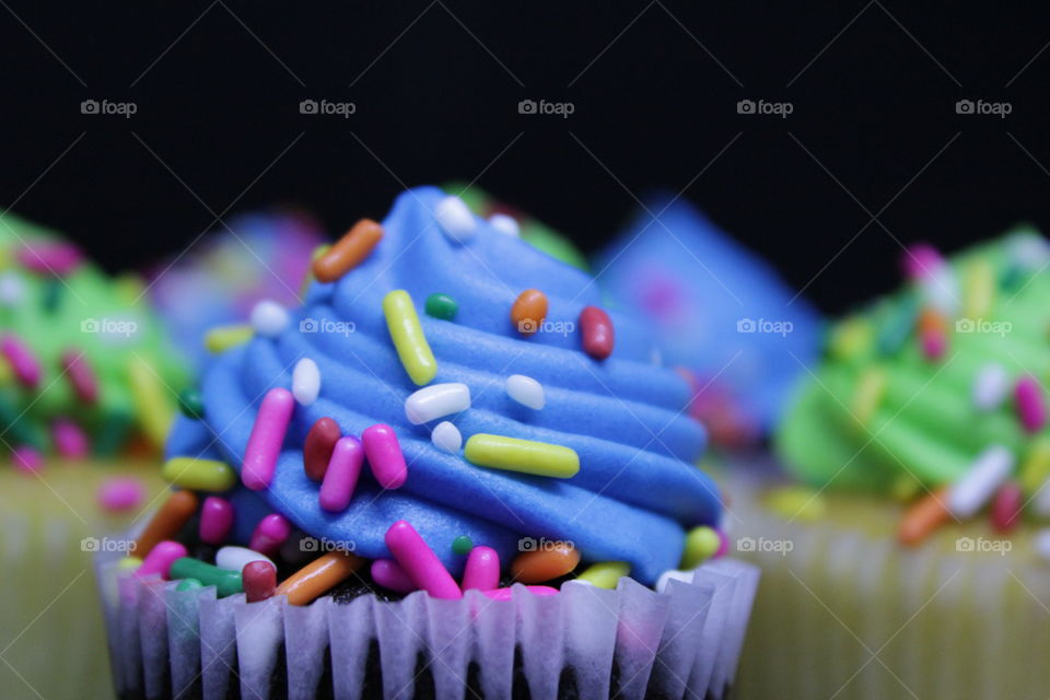 Mini cupcakes with blue and green frosting with multicolored sprinkles