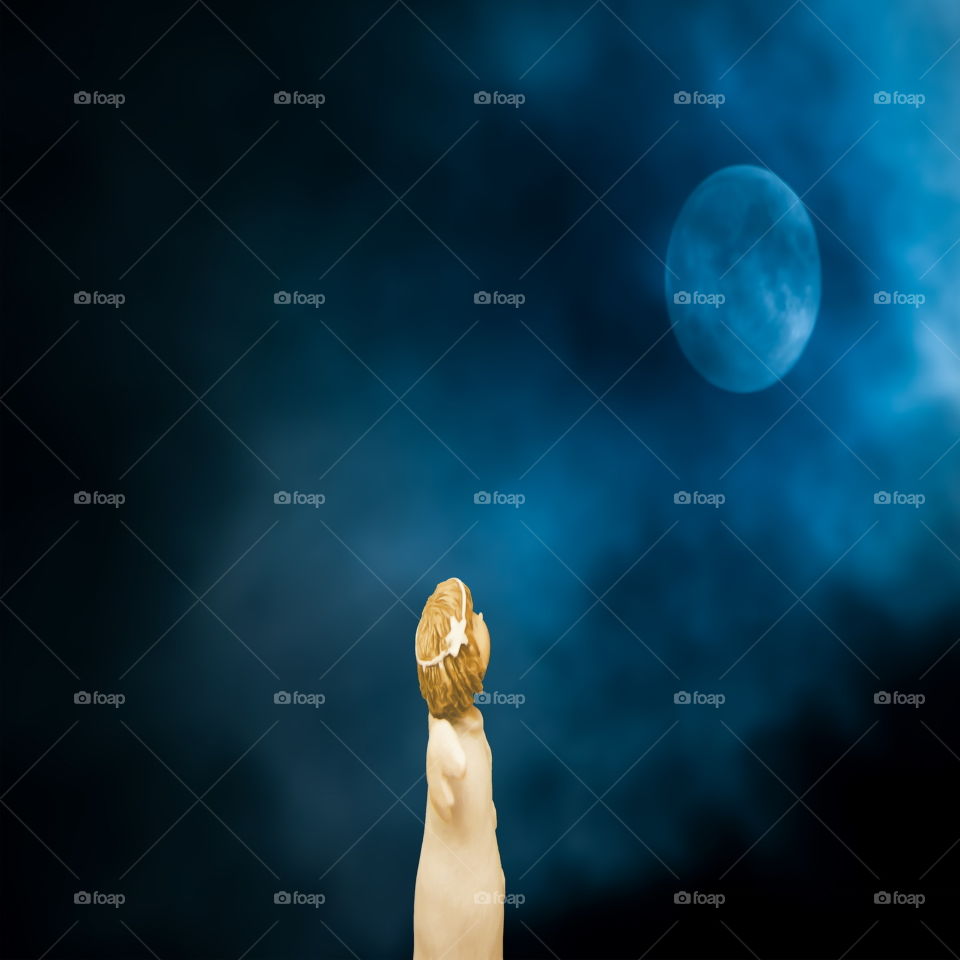 A small angel girl is watching the moon. A blue Christmas image