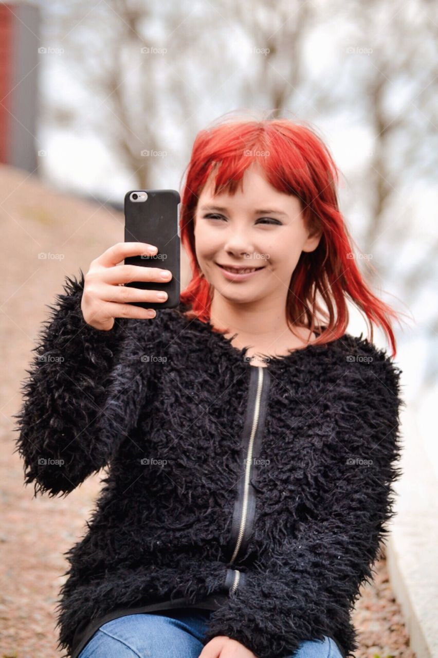 Happy girl with her phone taking a selfie