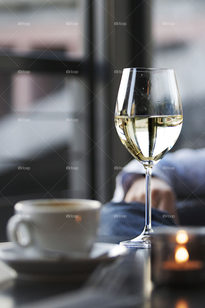 Wine glass and cup of coffee on table at a cafe