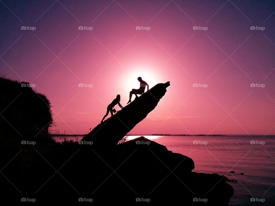 Silhouette of people on rock during sunset