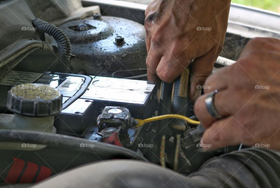 Vehicle maintenance: close-up on hands changing a car battery at home.