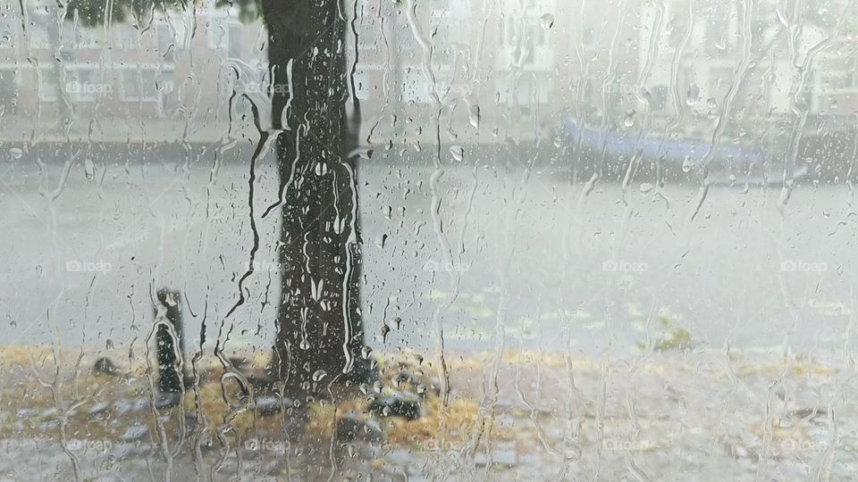 Looking out of the window to the rainy weather, while rain drops down the window