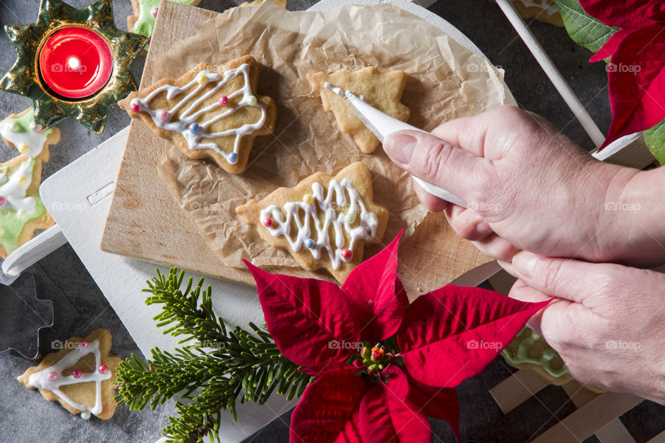 homemade cookies for the new year and christmas in the form of trees and animal figurines, a woman's hand covers the cookies with icing