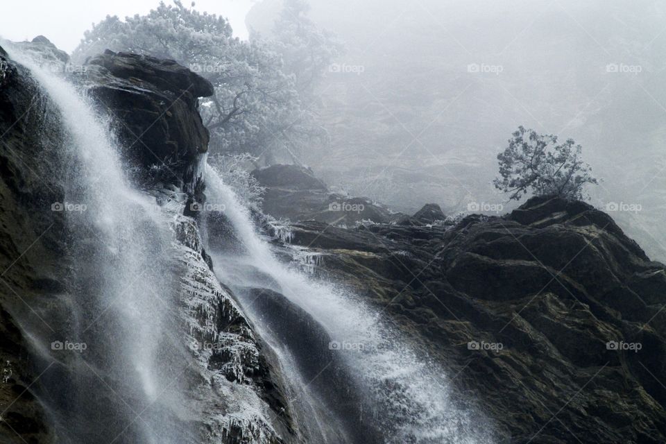 beautiful waterfall in the mountains in winter in the foggy
