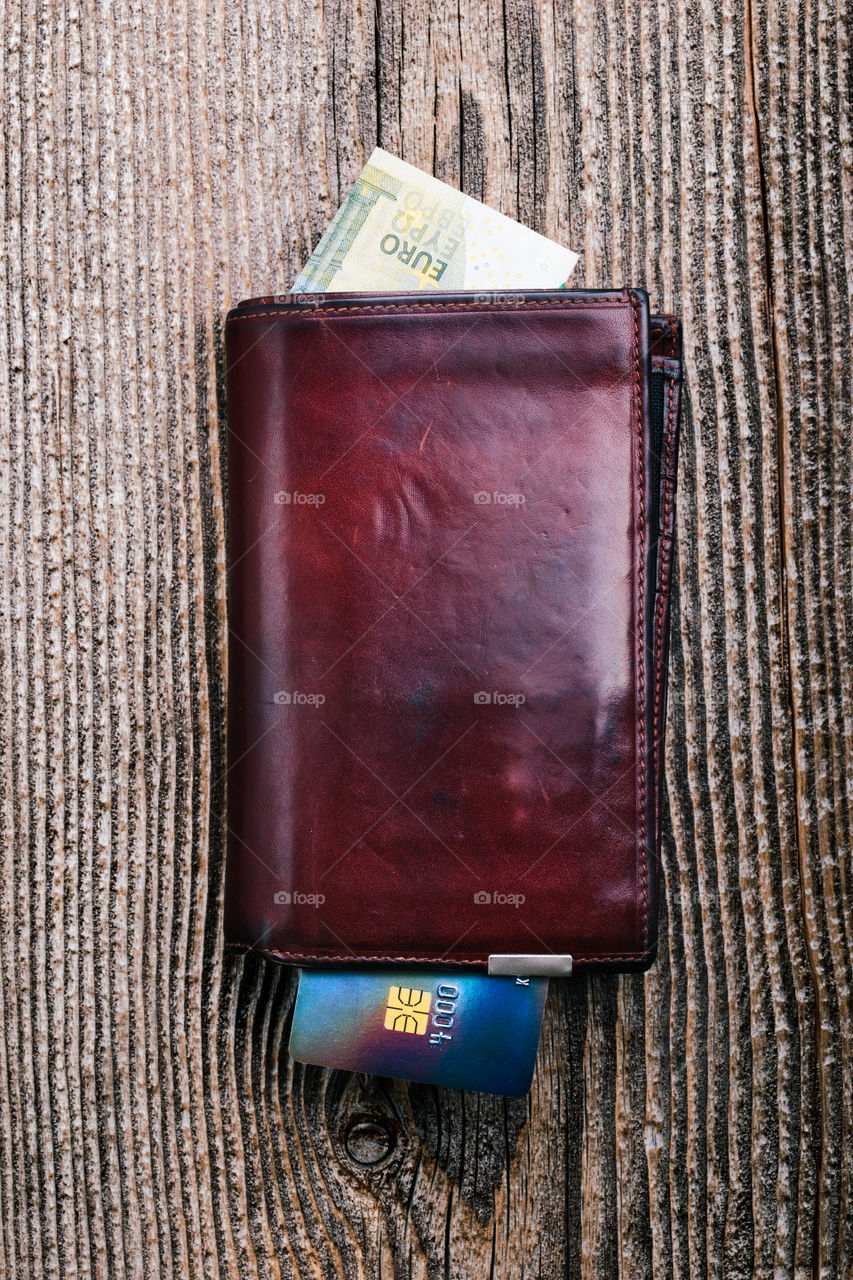 Leather wallet with euro banknotes, credit card on wooden desk. Portrait orientation
