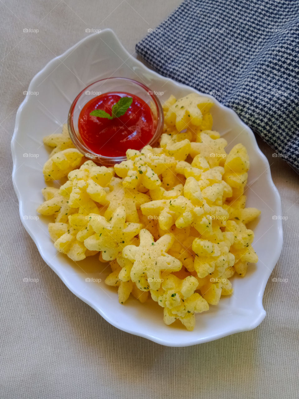 Tea time savoury snacks with tomato ketchup garnished with fresh mint  leaves .