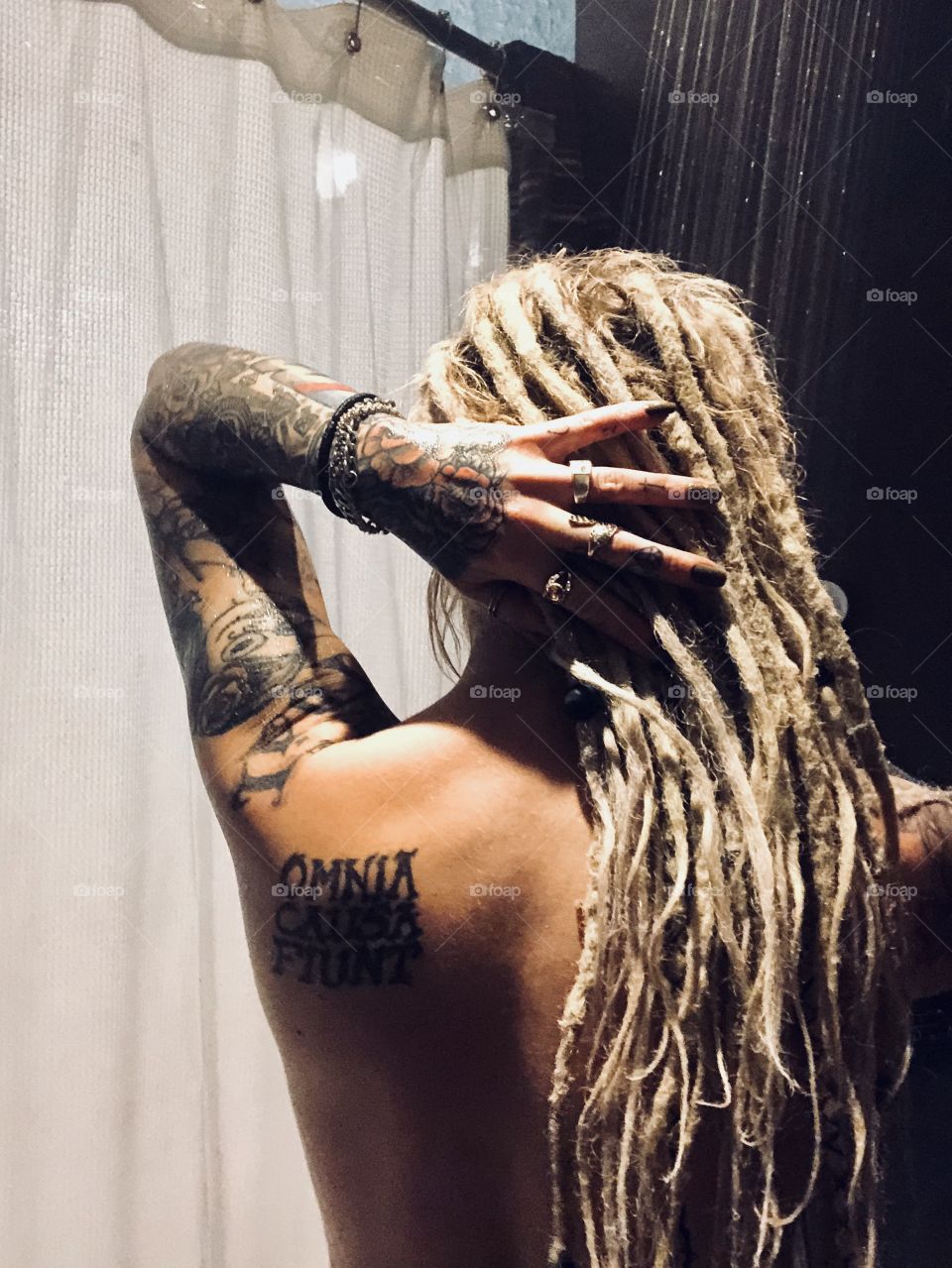 Blonde girl with dreadlocks and tattoos takes a shower 
