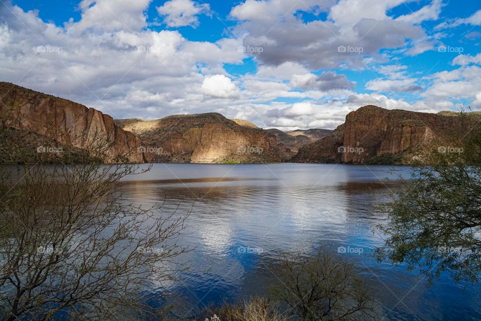 The rock walls that surround Arizona's Canyon Lake are dotted with shade and sun on a cloudy day