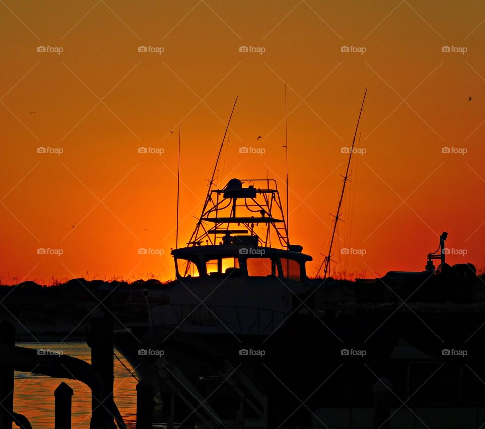 This magnificent sunset illustrates the fishing vessel - The big orange and crimson ball slowly going down and down and it sets into the horizon making the sky absolutely stunning.