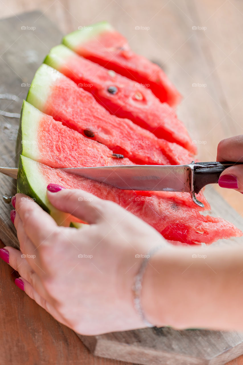 Young woman cutting juicy sweet watermelon for dessert. Moods of summer.