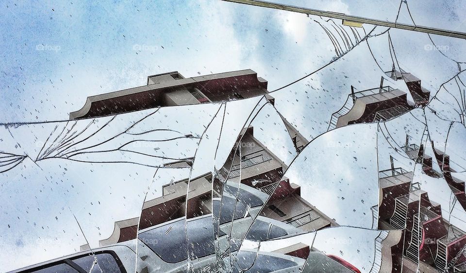 Buildings reflected in a broken mirror on a sidewalk
