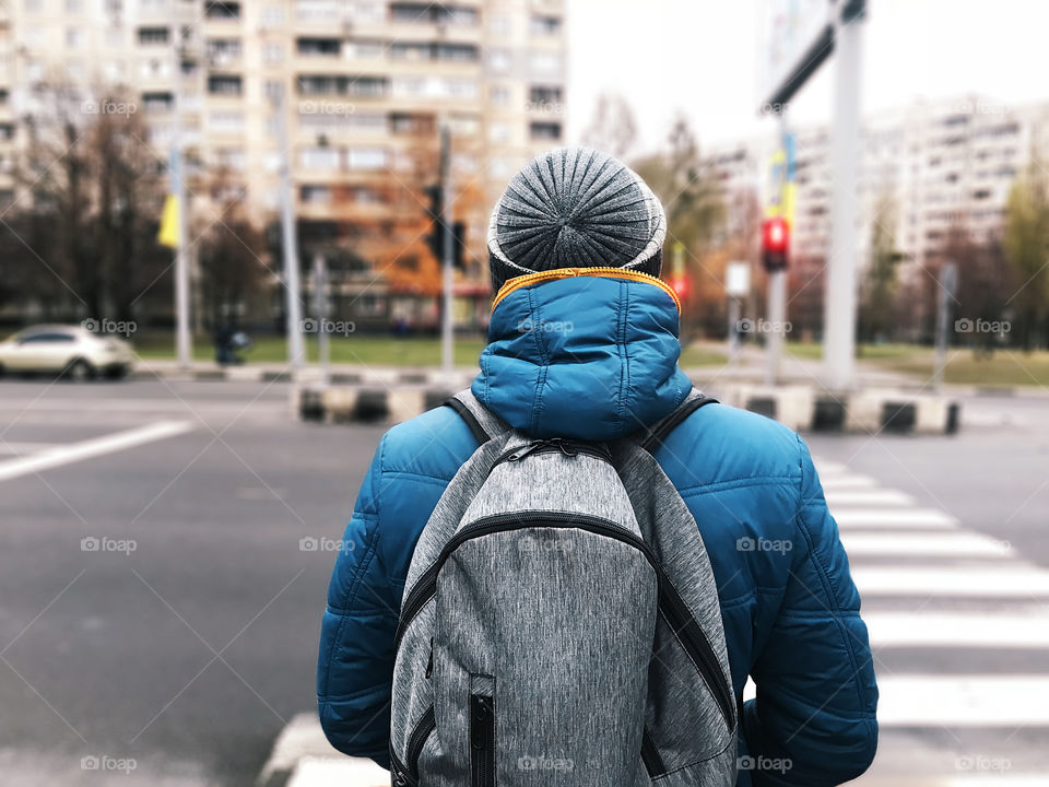 Young man hiking with a backpack through the autumn city 