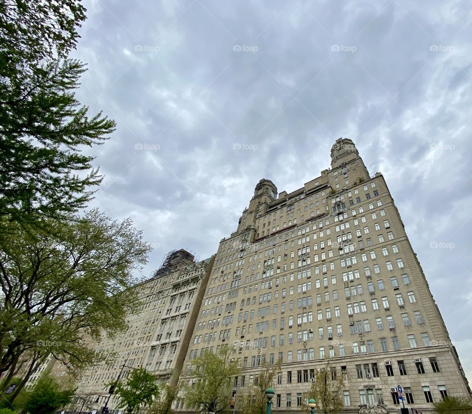 Tall building, with trees, skies and cloudy day. Structure of a building. Landscape.