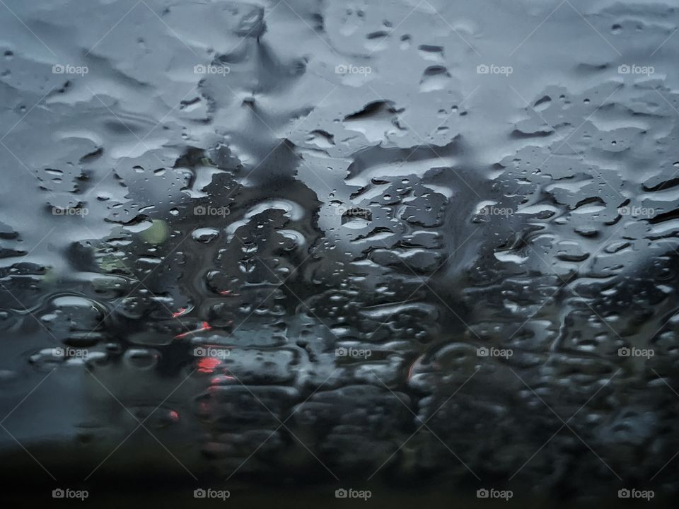 rain falling down on a gloomy spring morning as a car passes the window on the street