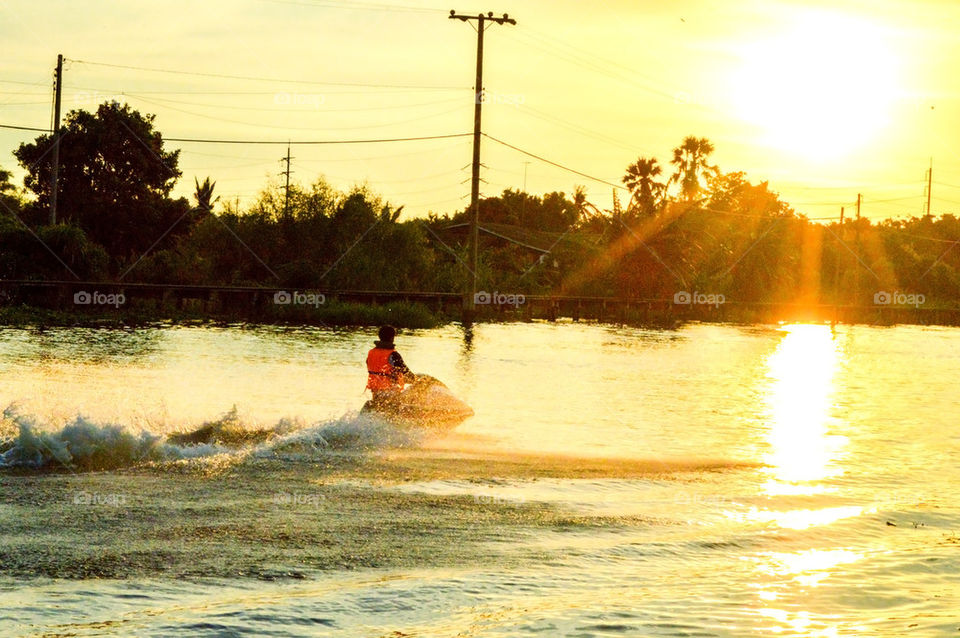  A man playing jet ski in sunset