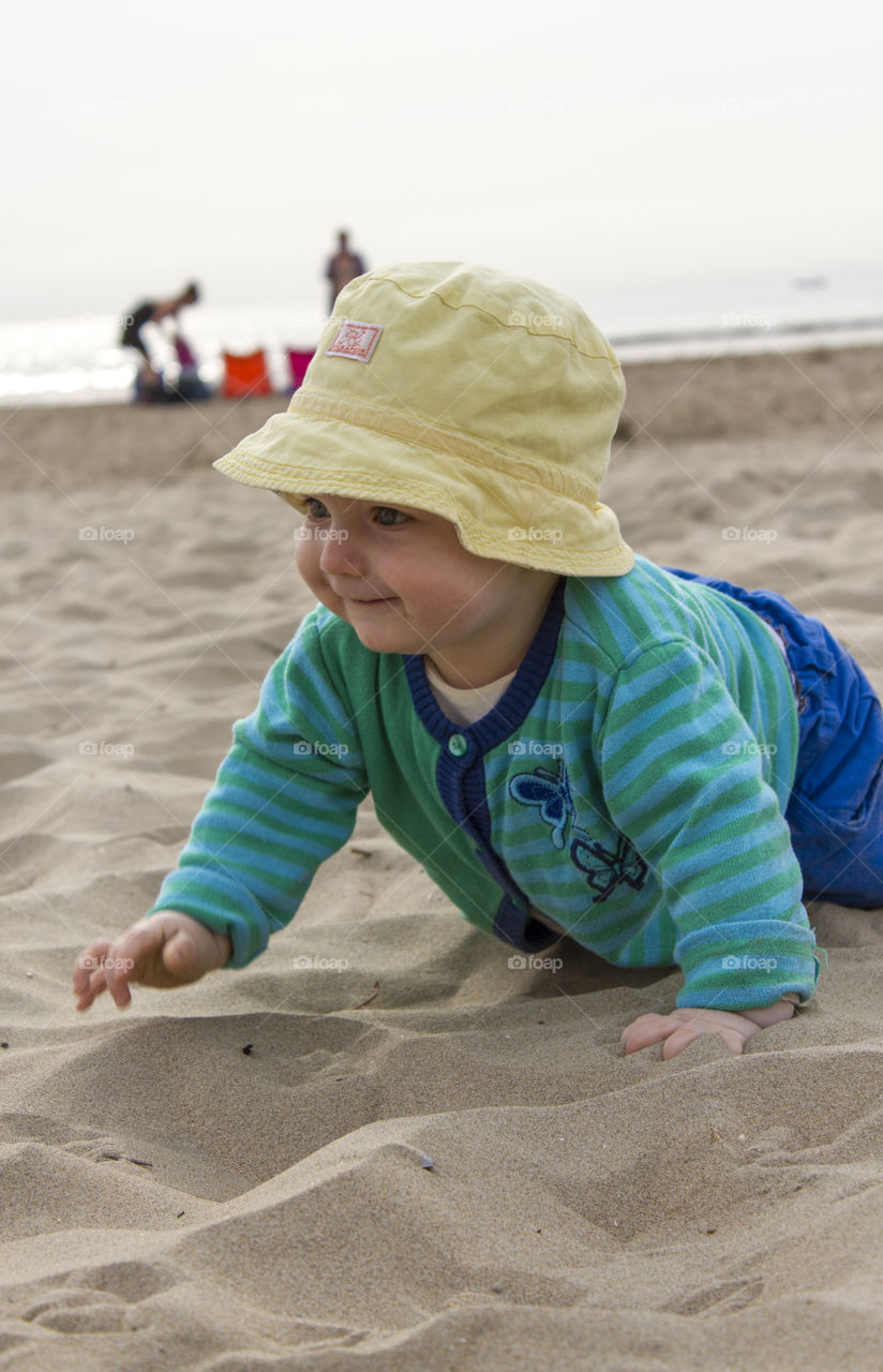 Cute boy crawling on sand
