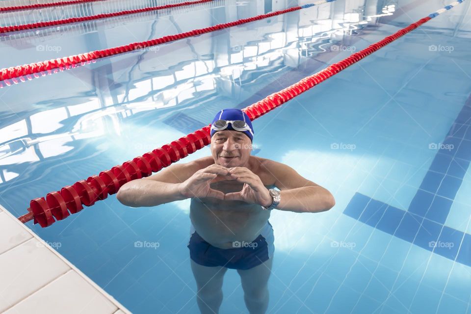A happy, elderly man is relaxing on vacation in the pool, playing sports and leading an active and healthy lifestyle.