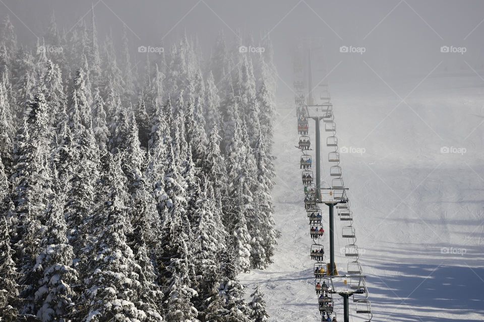 Ski lift packed with skiers going up in the fog