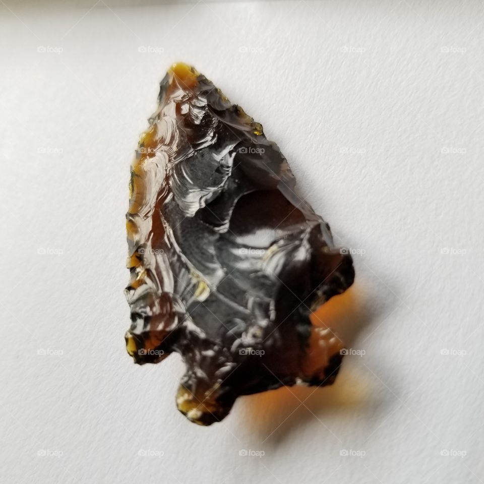 Knapped from the bottom of a brown glass bottle, this arrowhead is one of a kind.