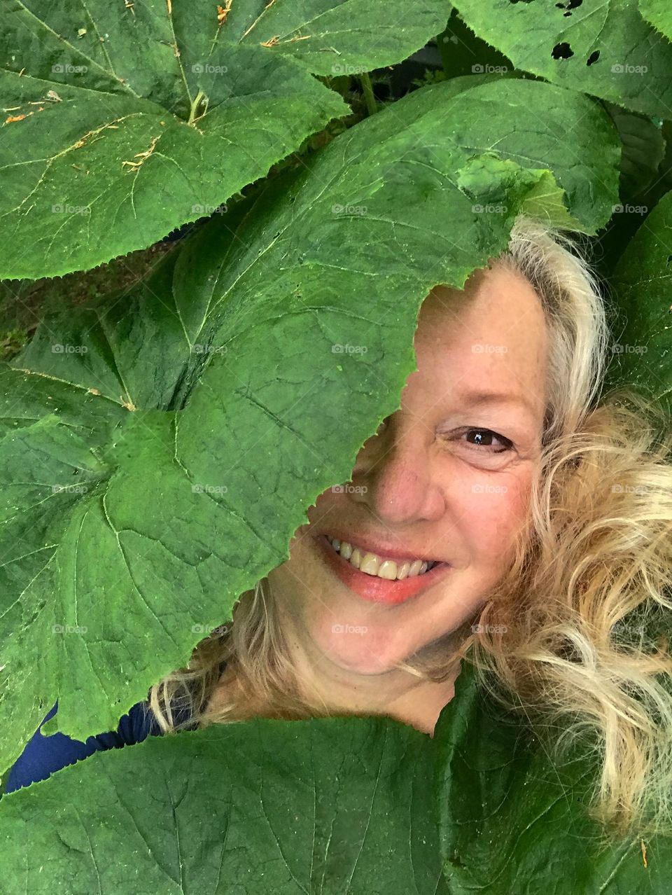 What’s that woman doing hiding under the umbrella plants?? Selfie of me lying down with my smiling face peeking out from between the leaves. 