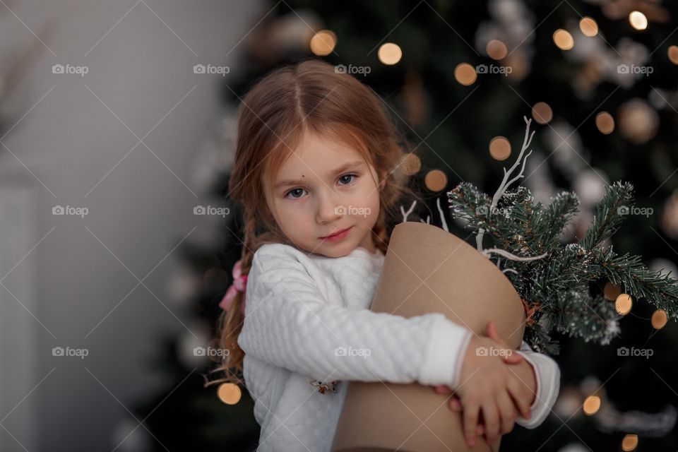 Little girl near Christmas tree at home