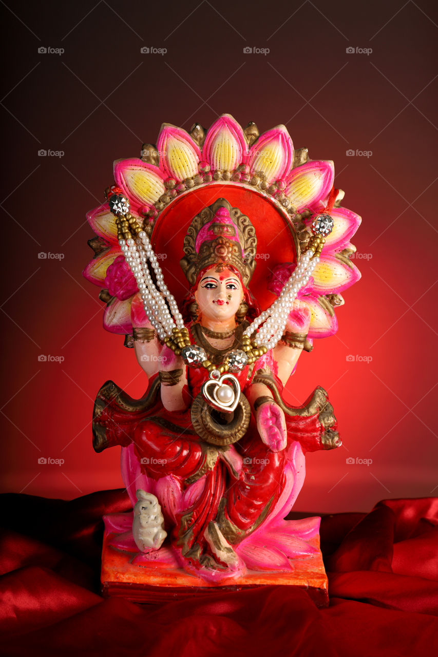 Hindu refilling goddess Laxmi on satin and red background