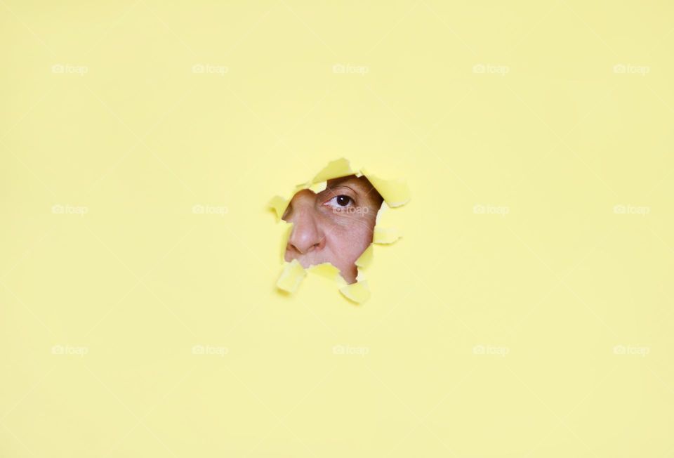 Woman hiding in a hole of paper