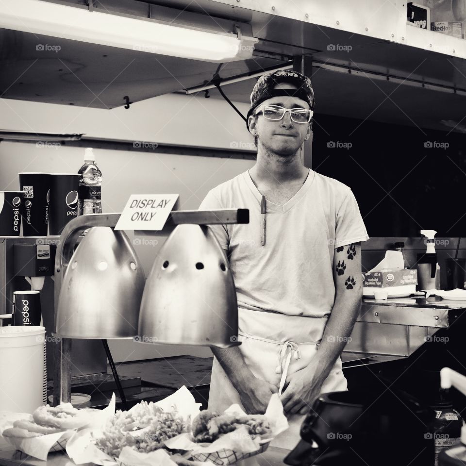 A young man working a food stand at a local carnival 